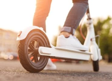 Close-up of a man riding an electric scooter in a city.