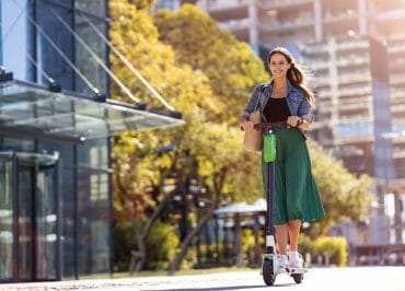 Carefree young woman riding an electric scooter.